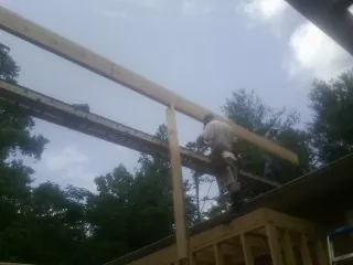 Carpenter setting a ridge beam over a new addition frame — Ice Dam Removal by Roofing Brothers in Warner
