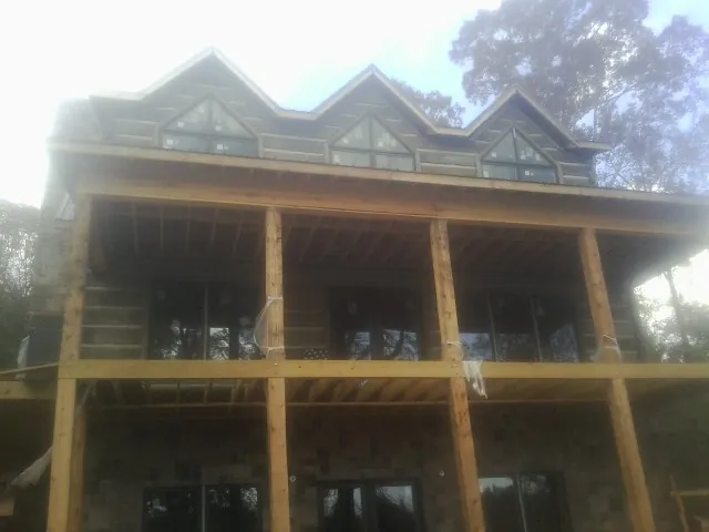 Dormers and porch framing on a large log home under construction — Roof Coating work by our crew in Warner