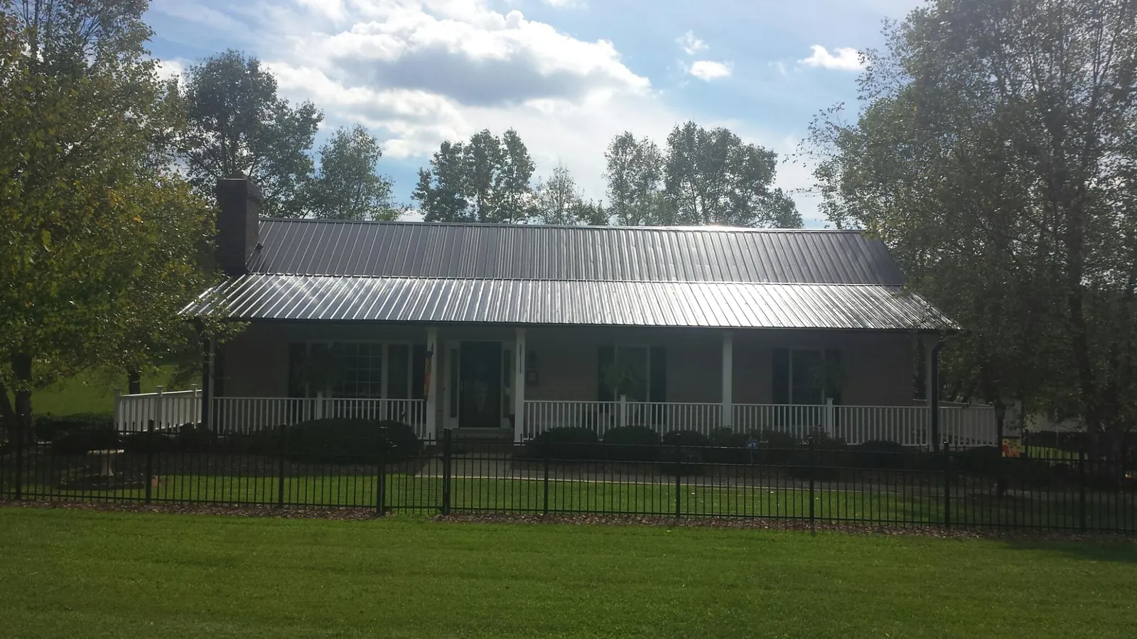 Gray metal roof on a brick ranch with a full width front porch — Gutter Guard Installation work by our crew in Warner