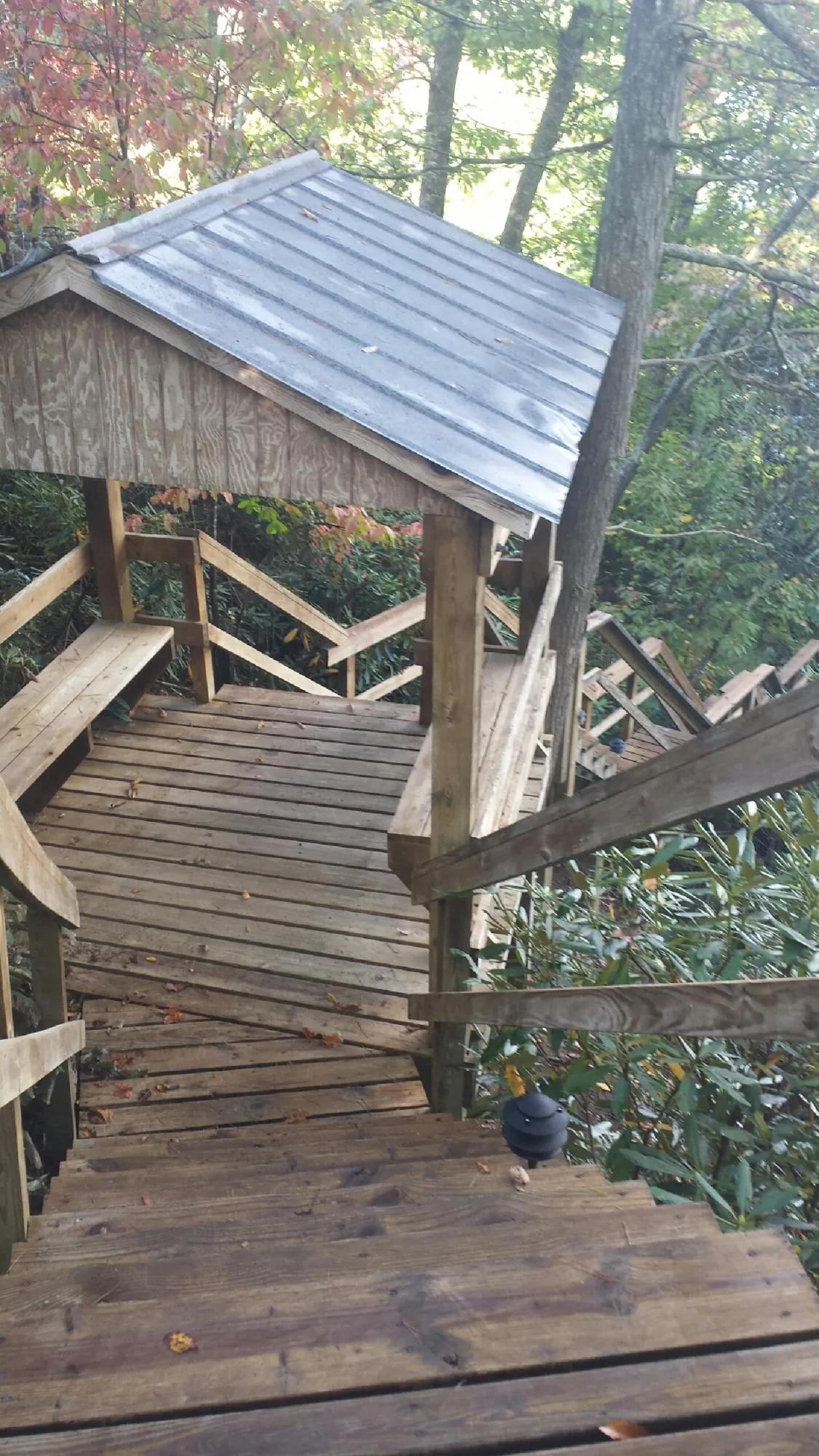 Metal roofed shelter over wooden steps on a wooded walkway — Skylight Repair & Installation work by our crew in Warner