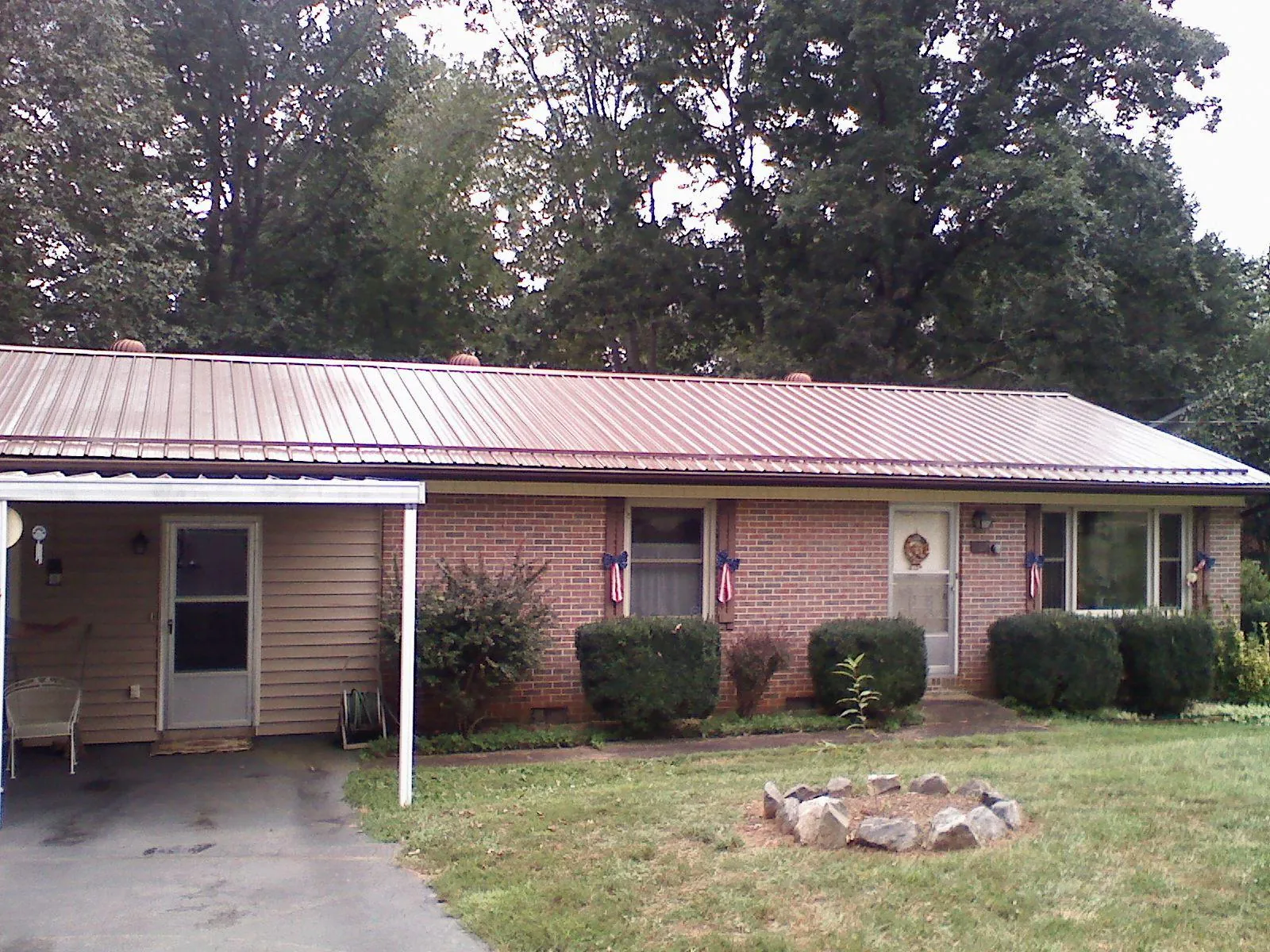 Bronze metal roof and carport on a brick ranch home — Roof Repair work by our crew in Warner